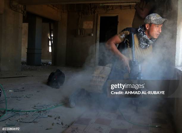 Fighter from Iraq's elite Counter-Terrorism Service takes cover inside a building in the Shuhada neighbourhood of west Mosul on March 10 during an...