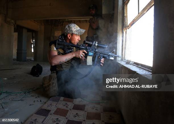 Fighter from Iraq's elite Counter-Terrorism Service takes cover inside a building in the Shuhada neighbourhood of west Mosul on March 10 during an...