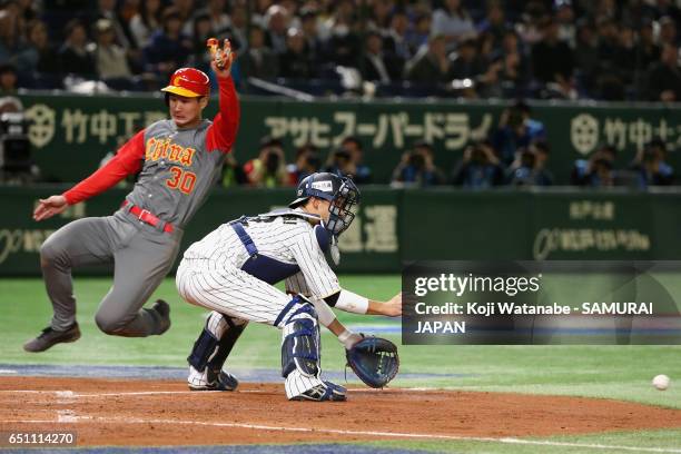 Catcher Seiji Kobayashi of Japan unable to tag as Infielder Fujia Chu of China slides safely into the home plate in the top of the third inning...