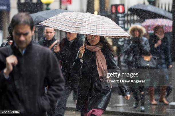 Commuters walk through a wintry mix of snow and sleet during the morning rush hour in the Financial District, March 10, 2017 in New York City. A...