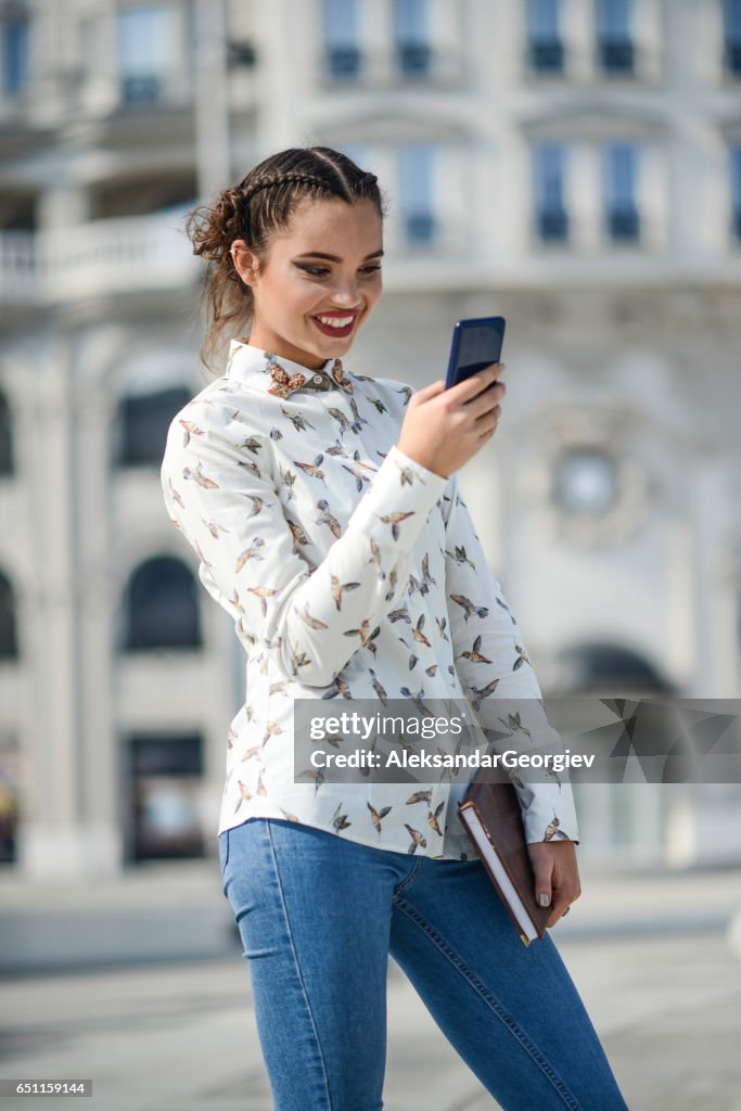 Étudiante souriante tenant le livre et le langage SMS sur Smartphone