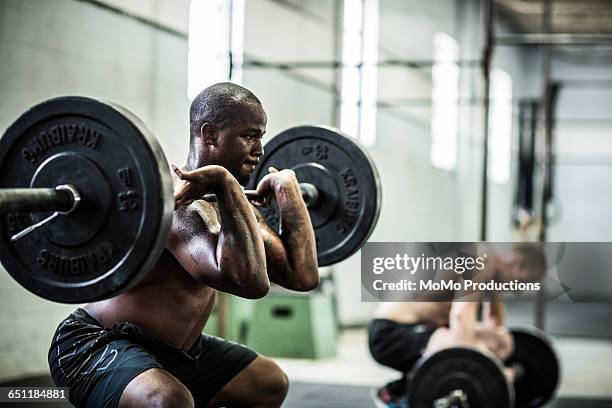 gym - men doing front squats - hombre agachado fotografías e imágenes de stock