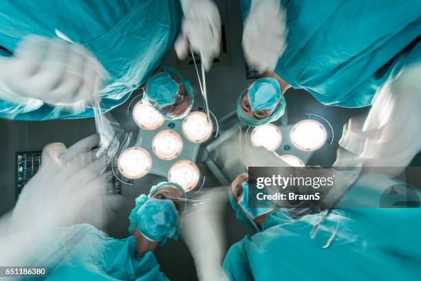 below view of surgeons performing a surgery in blurred motion. - sala de cirurgia com assistência imagens e fotografias de stock