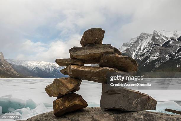 inuksuk rocks piled above frozen lake - inukshuk stock pictures, royalty-free photos & images