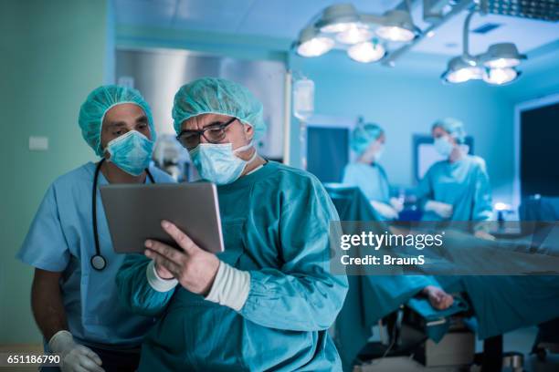 two medical experts using palmtop in operating room. - electronic organizer stock pictures, royalty-free photos & images