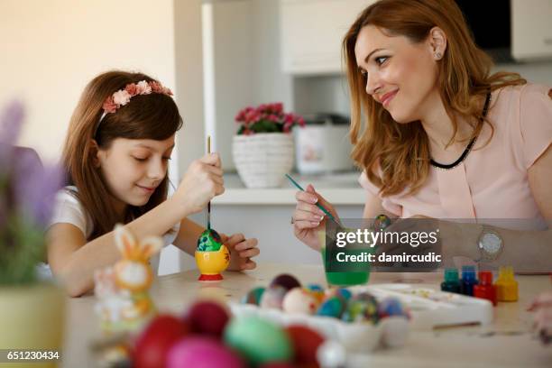 gelukkig moeder met dochters thuis paaseieren schilderen - happy easter mom stockfoto's en -beelden