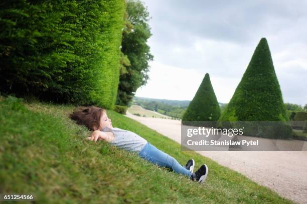 small girl lying on grass - newnaivetytrend stock-fotos und bilder