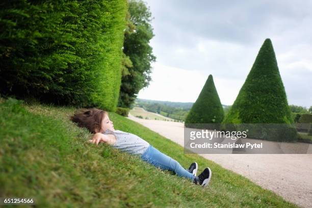 small girl lying on grass - newnaivetytrend ストックフォトと画像