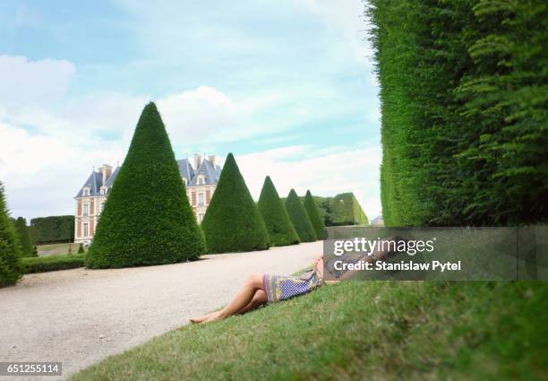 woman lying on grass in park - topiary - fotografias e filmes do acervo