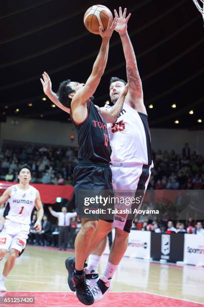 Shohei Kikuchi of the Alvark Tokyo tries to shoot under pressure from Josh Harrellson of the Osaka Evessa during the B. League match between Alvark...