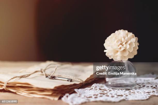 love letters and white flower in a small glass bottle on a wooden table - love books stock-fotos und bilder