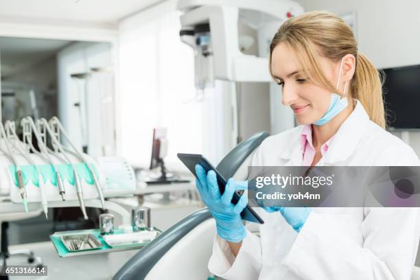 female dentist touching tablet at the clinic - dental record stock pictures, royalty-free photos & images