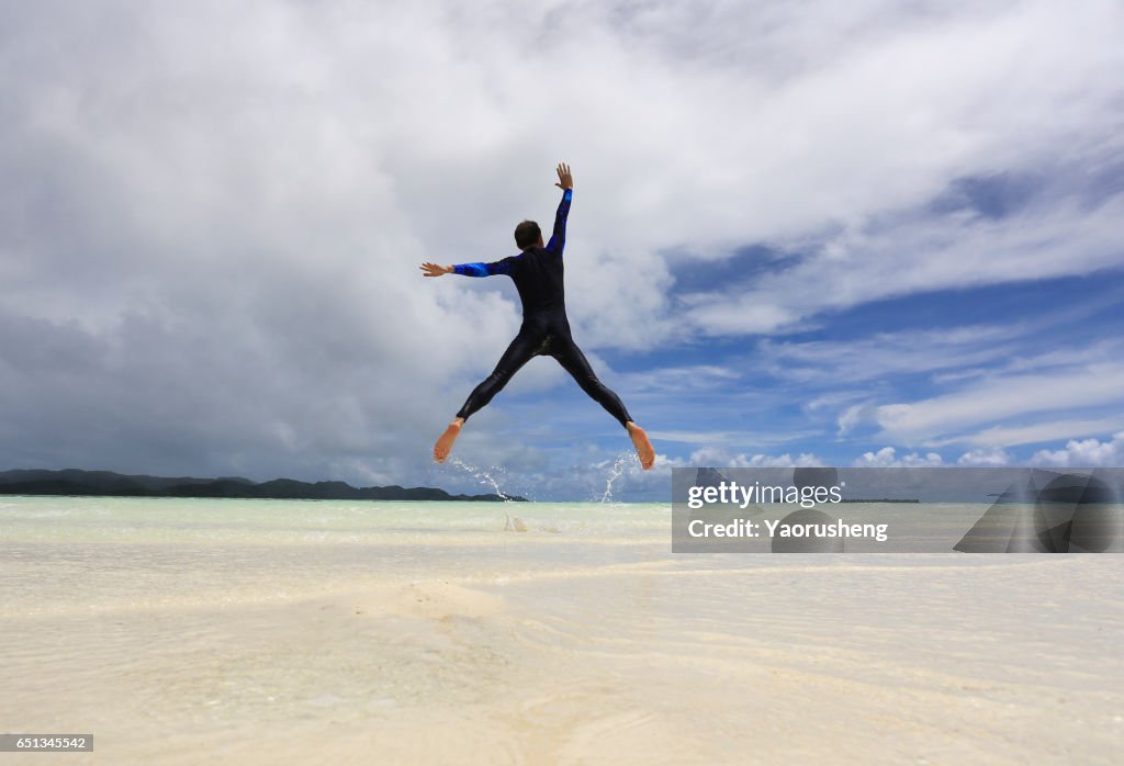 A Man Jumping on a Tropical White Sand Beach of Palau