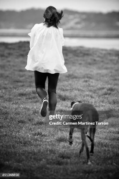 back view of young woman running after her greyhound dog - greyhound stock pictures, royalty-free photos & images