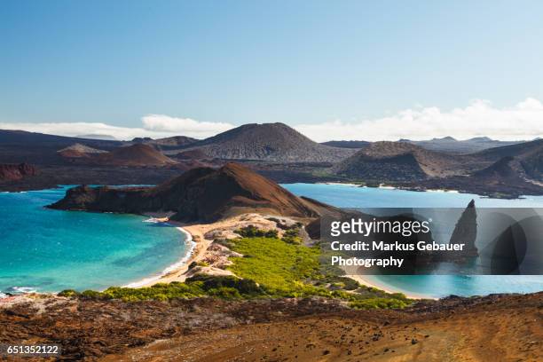 view on the volcanic landscape of bartolome island with famous pinnacle rock and golden beach, galapagos islands, ecuador - ecuador stock-fotos und bilder