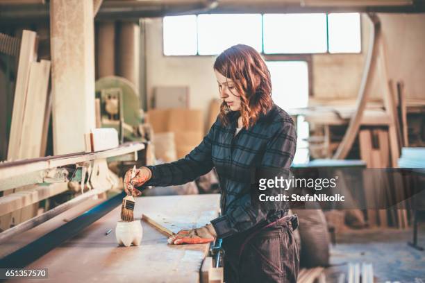 donna falegname ispezionando legno appena dipinto - wooden surface finishes foto e immagini stock