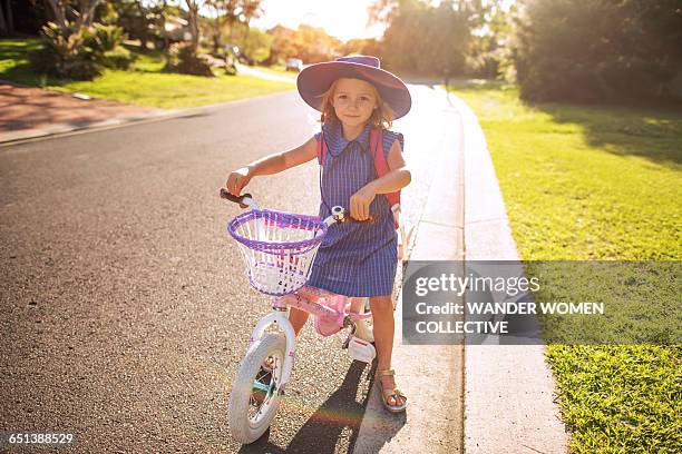 little girl off to school in uniform on her bike - hats off stock pictures, royalty-free photos & images