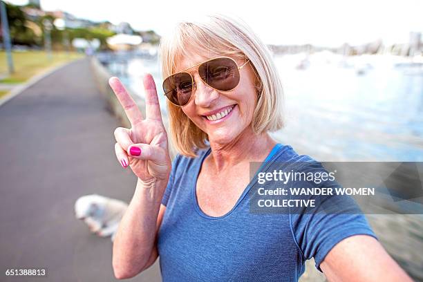 mature woman peace sign with dog and sunglasses - victory sign stock-fotos und bilder