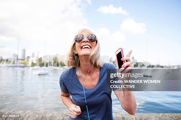 mature woman dancing to mpg with earphone - boardwalk australia stock pictures, royalty-free photos & images