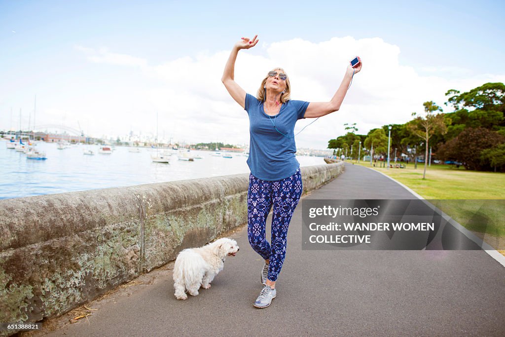 Mature woman with dog and MP3 dancing on street