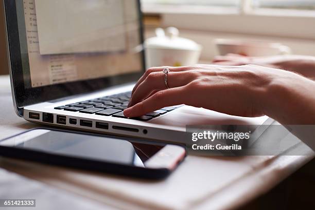 close up of young woman working remotely on laptop - close up phone on surface stock-fotos und bilder