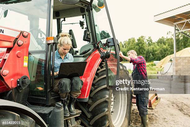 woman using laptop while man standing by tractor - farmhouse stock pictures, royalty-free photos & images