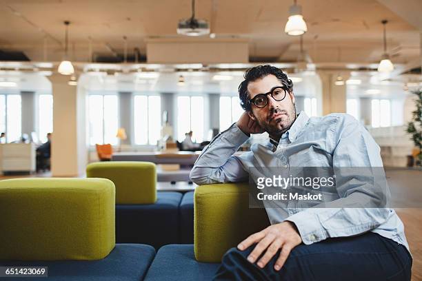 portrait of mature man sitting on couch at corridor - student visa stockfoto's en -beelden