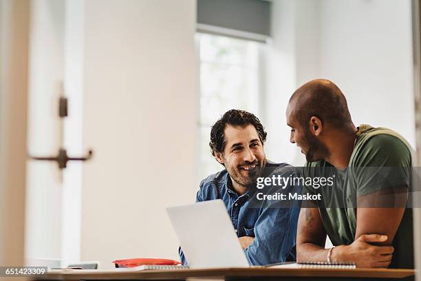 smiling friends talking while sitting in language class - student visa stockfoto's en -beelden