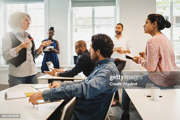 students writing while teacher explaining in language class - mature student stock pictures, royalty-free photos & images