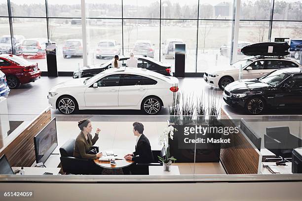 high angle view of saleswoman and customer discussing in meeting at showroom - car dealer stock pictures, royalty-free photos & images