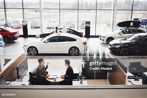 high angle view of saleswoman and customer discussing in meeting at showroom - car dealership imagens e fotografias de stock