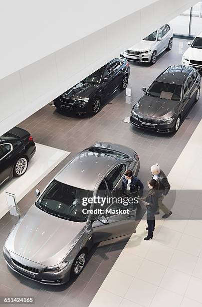 high angle view of saleswoman explaining to customers at car showroom - car inside showroom stock-fotos und bilder