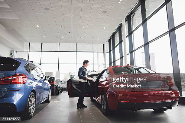 senior woman looking inside car in showroom - car dealership photos et images de collection