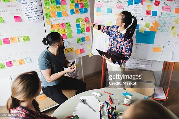 high angle view of businesswoman showing notes and explaining colleagues during meeting - engineers brainstorming stock pictures, royalty-free photos & images