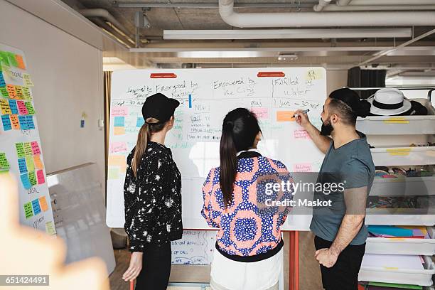 engineers looking at whiteboard in creative office - team looking at adhesive notes in board room during meeting stock-fotos und bilder