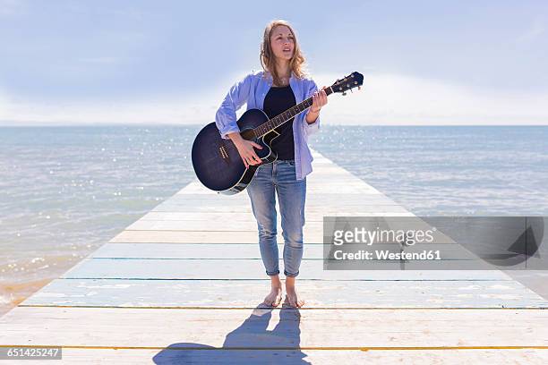 young woman with guitar on jetty - guitar ストックフォトと画像