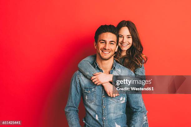 portrait of happy young couple in front of red background - mesma roupa imagens e fotografias de stock