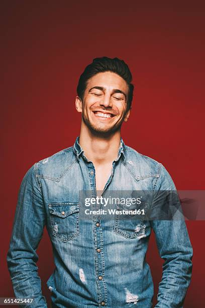 portrait of smiling young man with closed eyes - denim shirt stock pictures, royalty-free photos & images