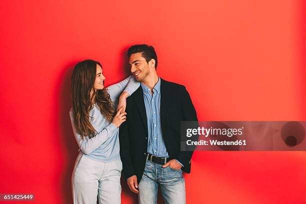 portrait of happy young couple in front of red background - heteroseksueel koppel stockfoto's en -beelden