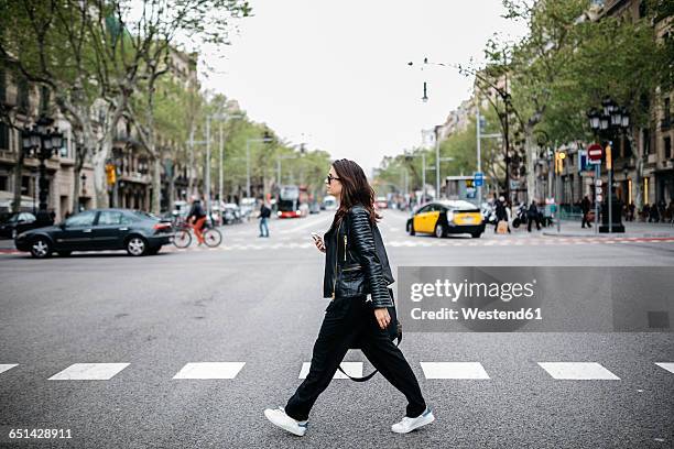 spain, barcelona, young woman in the city crossing street - street side stock-fotos und bilder