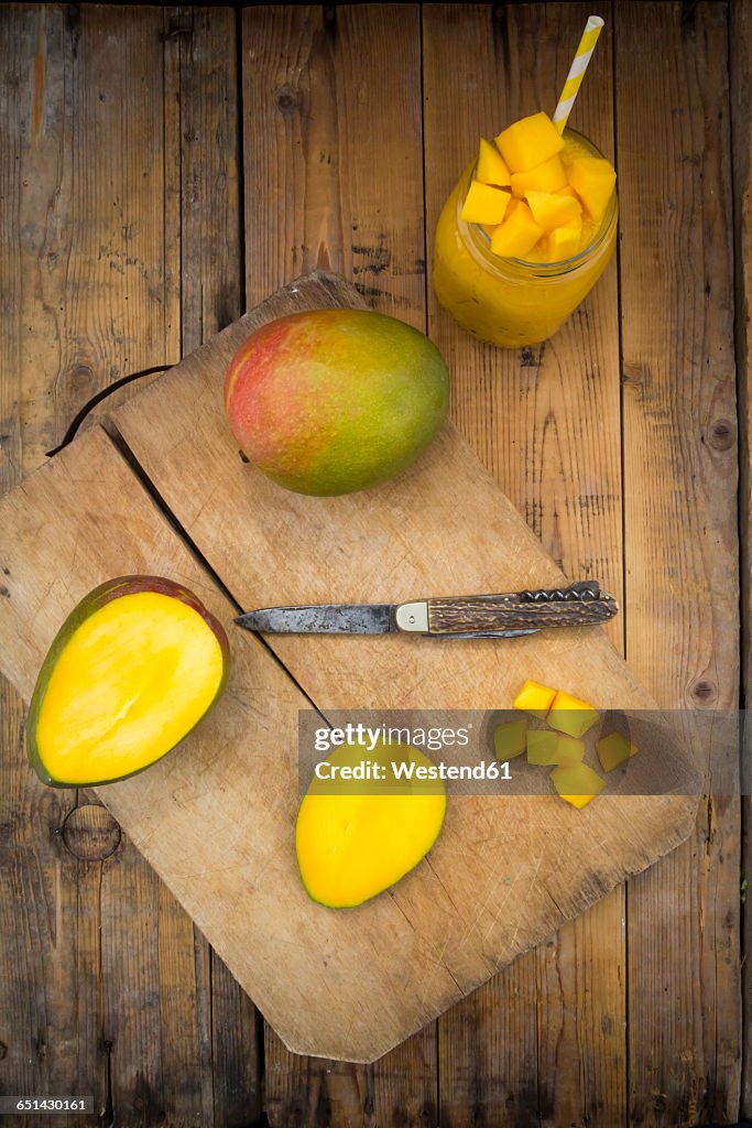 Glass of mango smoothie and whole and sliced mango