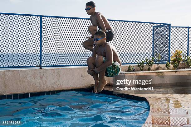 two boys doing a cannonball dive into swimming pool - cannonball pool stock pictures, royalty-free photos & images