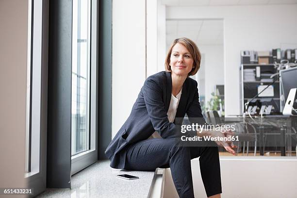 businesswoman sitting at the window - business woman looking through window stock pictures, royalty-free photos & images