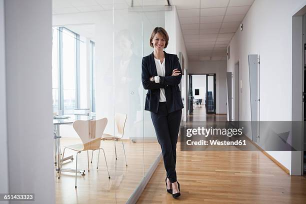 portrait of confident businesswoman in office hall - glass reflection in office stock-fotos und bilder