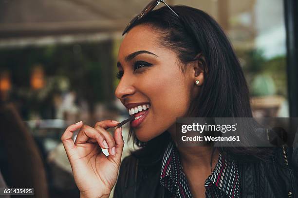 portrait of smiling young woman eating chocolate in a cafe - chocolate eating ストックフォトと画像