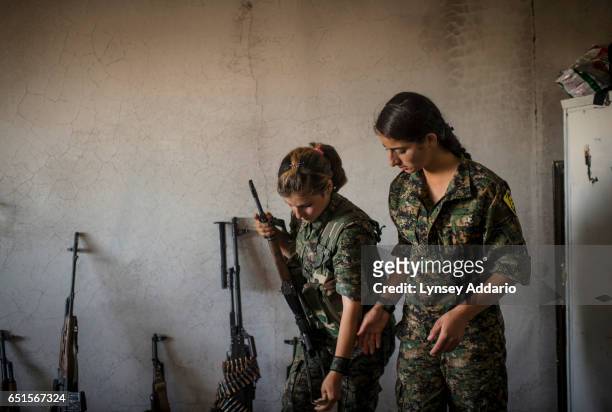 Fighter in training, Xwinda left, is helped by another female fighter as she prepares to pose for a portrait with her gun at a base in the former...