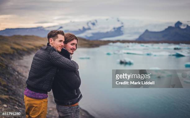 affectionate gay couple hugging at jokulsarlon glacier lagoon, iceland - jökulsárlón lagoon fotografías e imágenes de stock