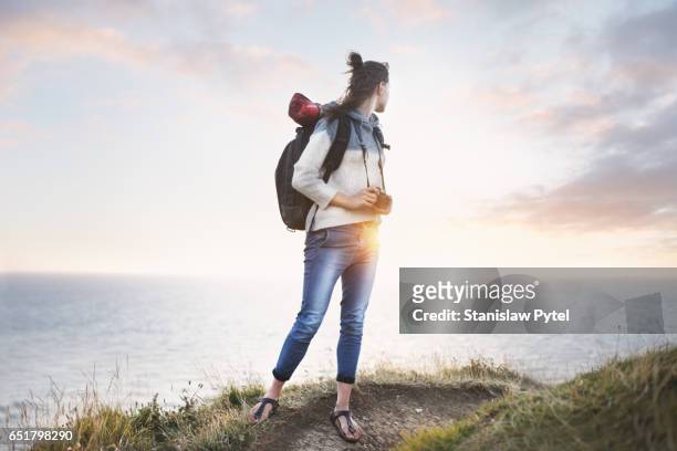 girl at edge of cliff looking at ocean - rolled up pants 個照片及圖片檔