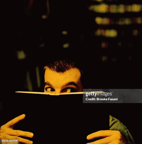 man hiding behind book - mystery book stock pictures, royalty-free photos & images