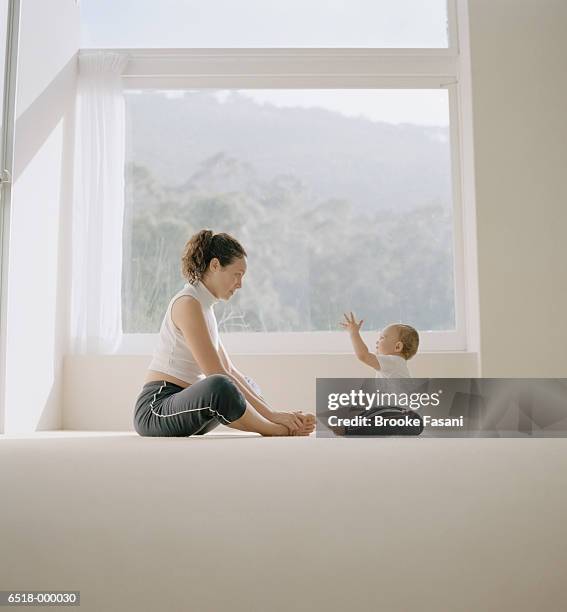 toddler exercising with mother - mum sitting down with baby stockfoto's en -beelden